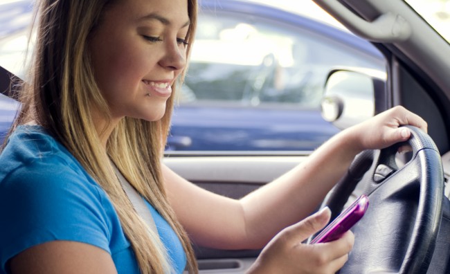 A teen girl texting while driving (Image: CDC/<b>Amanda Mills</b> [CC0 Public - A-teen-girl-texting-while-driving-Image-CDC-Amanda-Mills-Public-Domain-via-Freestockphotos-biz