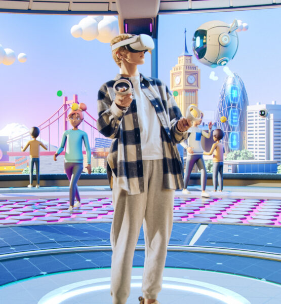 Ein Mensch trägt eine Virtual-Reality-Brille und Controller in den Händen. Er steht in einer futuristischen virtuellen Umgebung, die von Avataren bevölkert ist. Im Hintergrund sind stilisierte Gebäude und Wahrzeichen wie der Big Ben und eine moderne Skyline zu sehen. Die Umgebung wirkt bunt und dynamisch, mit verschiedenen Personen, die miteinander interagieren.
