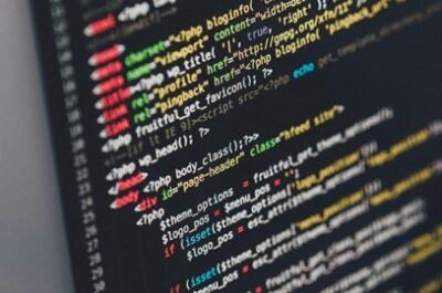 Das Bild zeigt einen Computerbildschirm mit farbigem Code, der vermutlich in einer Programmiersprache wie HTML, PHP oder JavaScript geschrieben ist. Der Code besteht aus verschiedenen Befehlen, Tags und Parametern, die in unterschiedlichen Farben angezeigt werden, um die Struktur zu verdeutlichen. Der Bildschirm wirkt dunkel, während der Code in leuchtenden Farben hervorsticht, was eine typische Arbeitsumgebung eines Programmierers oder Entwicklers darstellt.