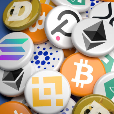 Das Bild zeigt eine Sammlung von Symbolen verschiedener Kryptowährungen, die als runde Buttons dargestellt sind und sich auf der rechten Seite des Bildes stapeln. Zu sehen sind unter anderem die Logos von Bitcoin, Ethereum, Solana, Binance, Dogecoin und anderen bekannten Kryptowährungen. Die linke Seite des Bildes ist leer und bietet einen kontrastierenden blauen Hintergrund, der die Aufmerksamkeit auf die Krypto-Buttons lenkt.