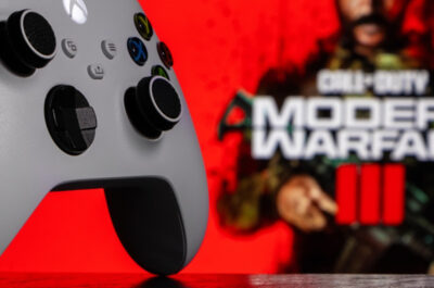 Ein Xbox Series Controller auf dem Tisch, im Hintergrund sieht man etwas verschwommen das Logo von Call of Duty: Modern Warfare 3.