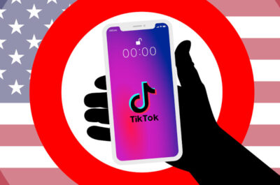 Ein Verbotsschild mit einem in der Hand gehaltenen Handy auf der TikTok läuft. Im Hintergrund ist die amerikanische Flagge zu sehen.